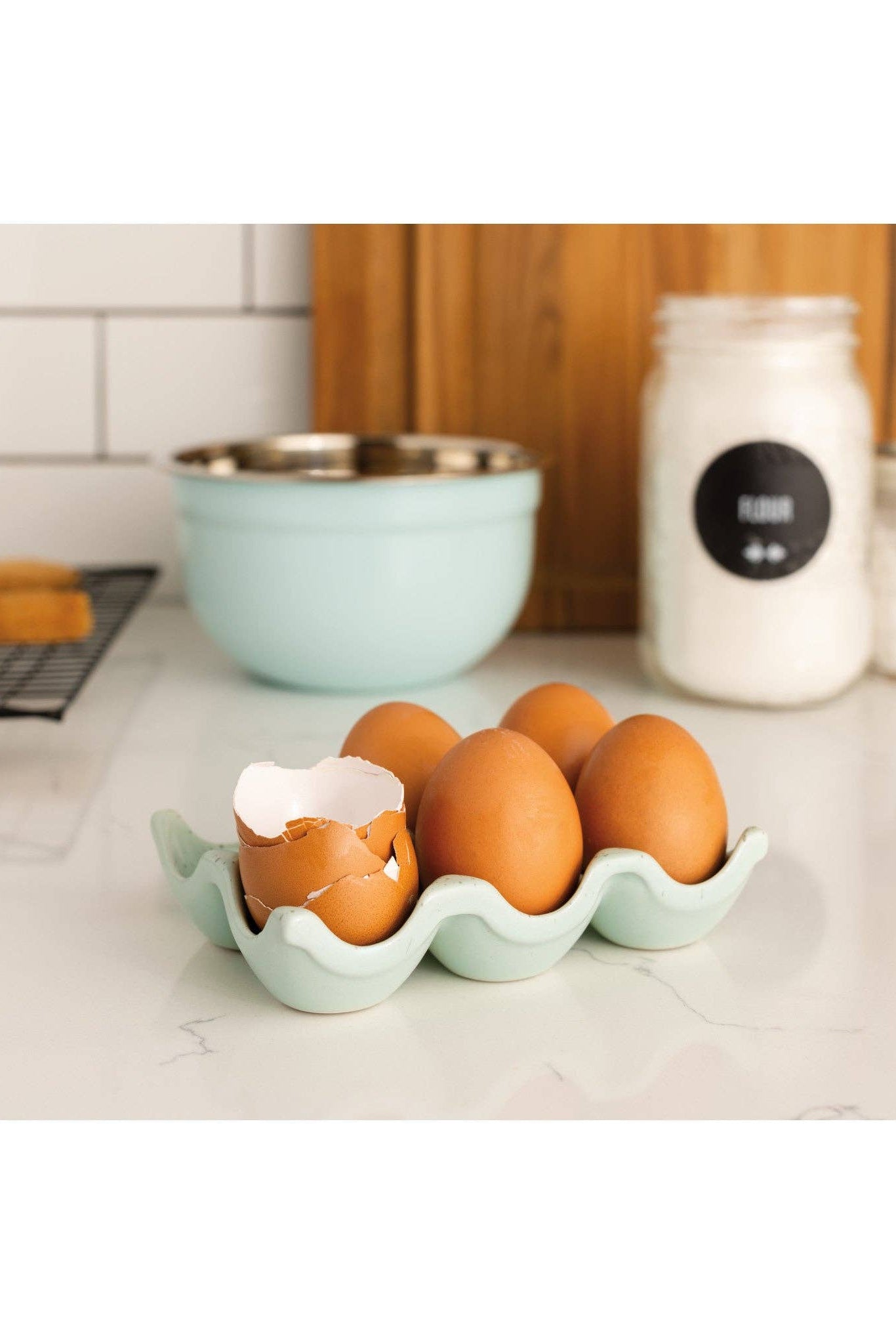 Green egg holder with cracked eggs on a kitchen counter